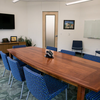 A long wooden table is surrounded by blue upholstered chairs.