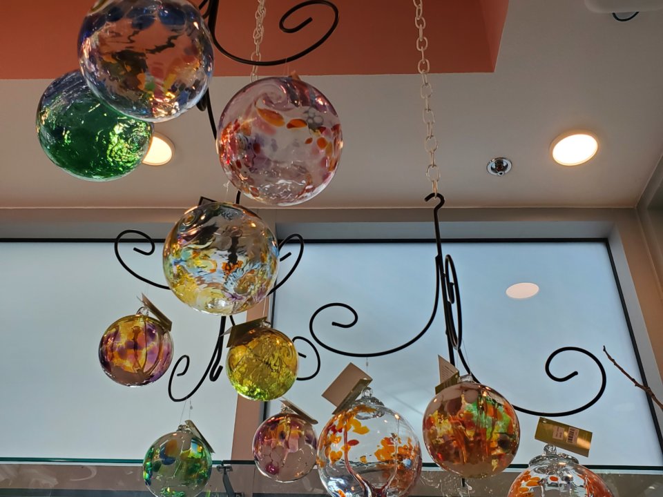 Painted glass balls hang from a display inside the Tilted Tulip gift shop.