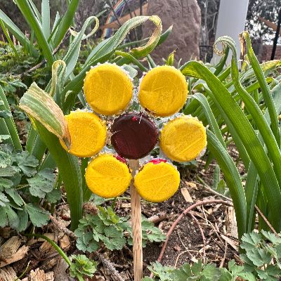 Yellow flower bottle caps with a wooden stick