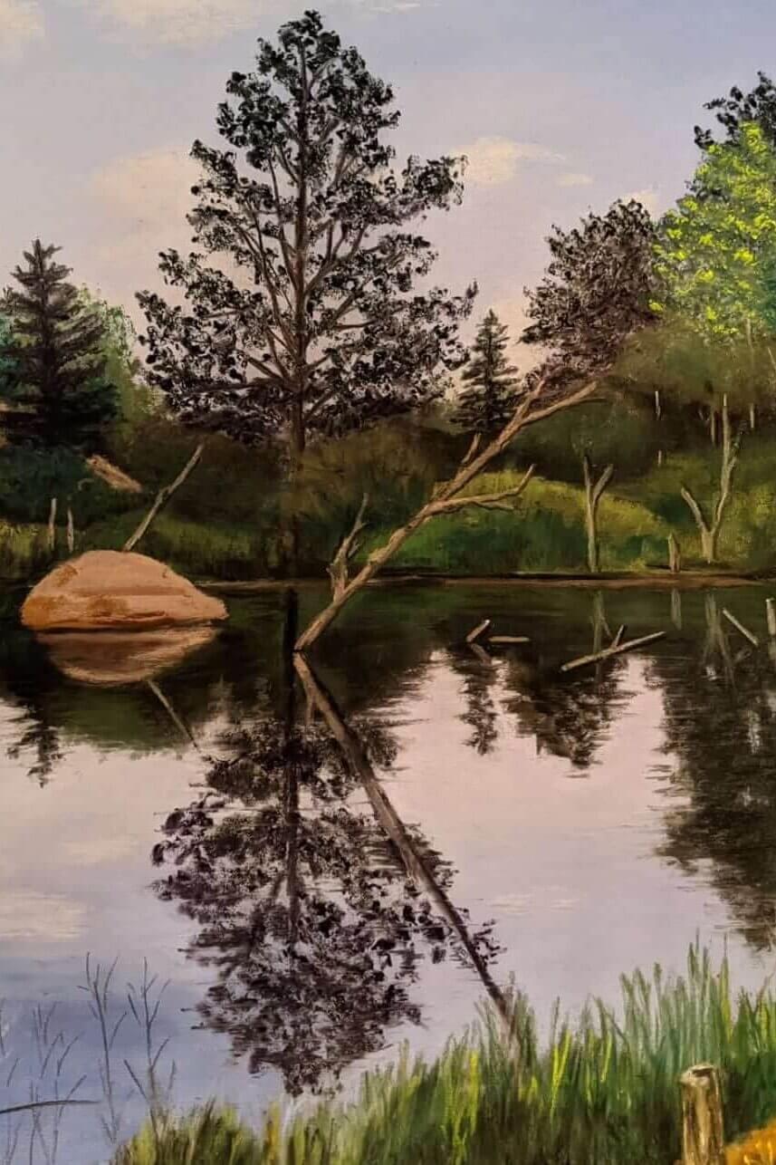 Landscape painting of a calm pond surrounded by trees and large rocks, with reflections mirrored in the still water. A fallen tree extends across the pond, while tall grasses line the foreground under a soft, cloudy sky.
