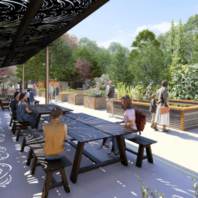 A wide outdoor community garden and gathering space with long black picnic tables under a decorative metal canopy casting patterned shadows across the seating area.