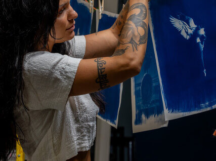 CariFaye hanging fabric cyanotypes on a line with clothes pins.