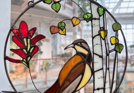 Stained glass art pieces with a robin surrounded by nature