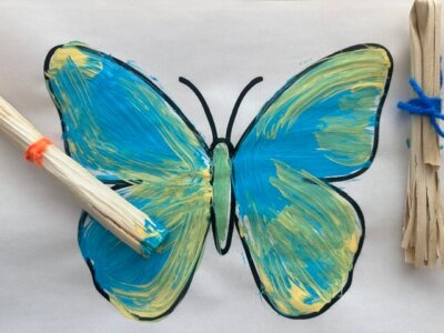 homemade corn husk paintbrush and a blue and green painted butterfly.